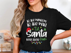 Black t-shirt with white text "To the window to the wall 'til Santa decks these halls."