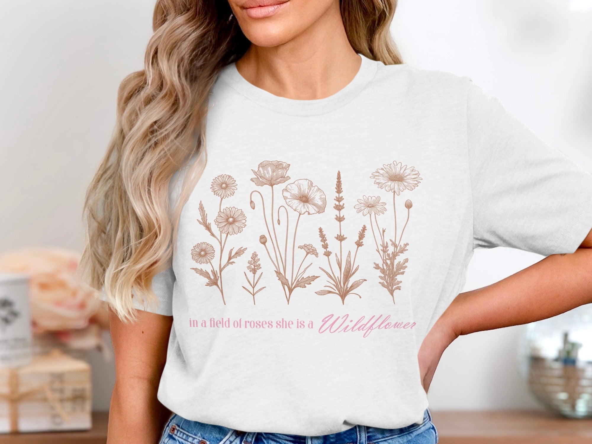 White t-shirt with line drawing flowers and "in a field of roses she is a Wildflower"