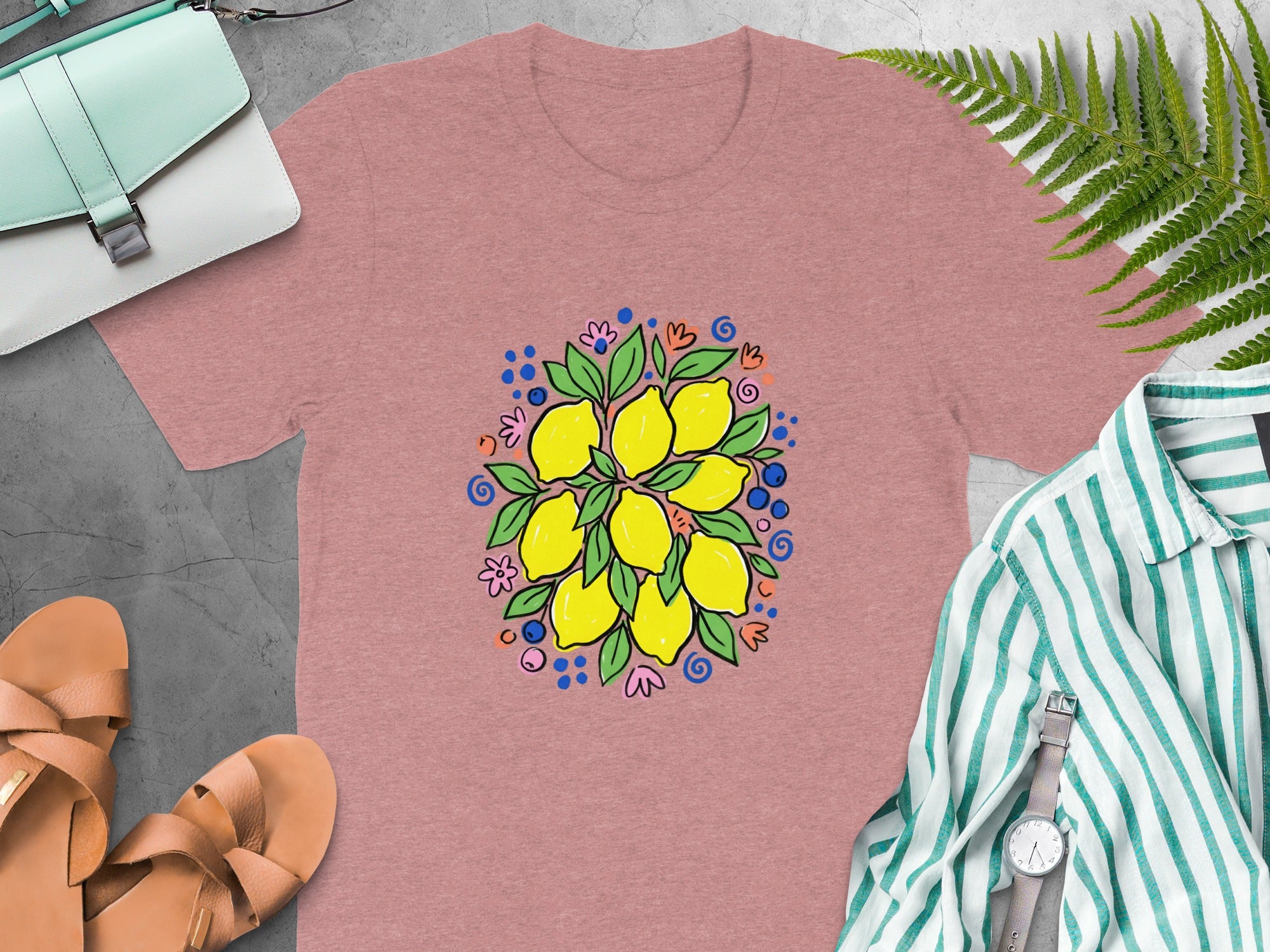 Pink t-shirt with a colorful lemon and blueberry illustration and surrounding floral details.