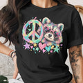 Black t-shirt with a colorful raccoon wearing heart sunglasses and a peace sign.