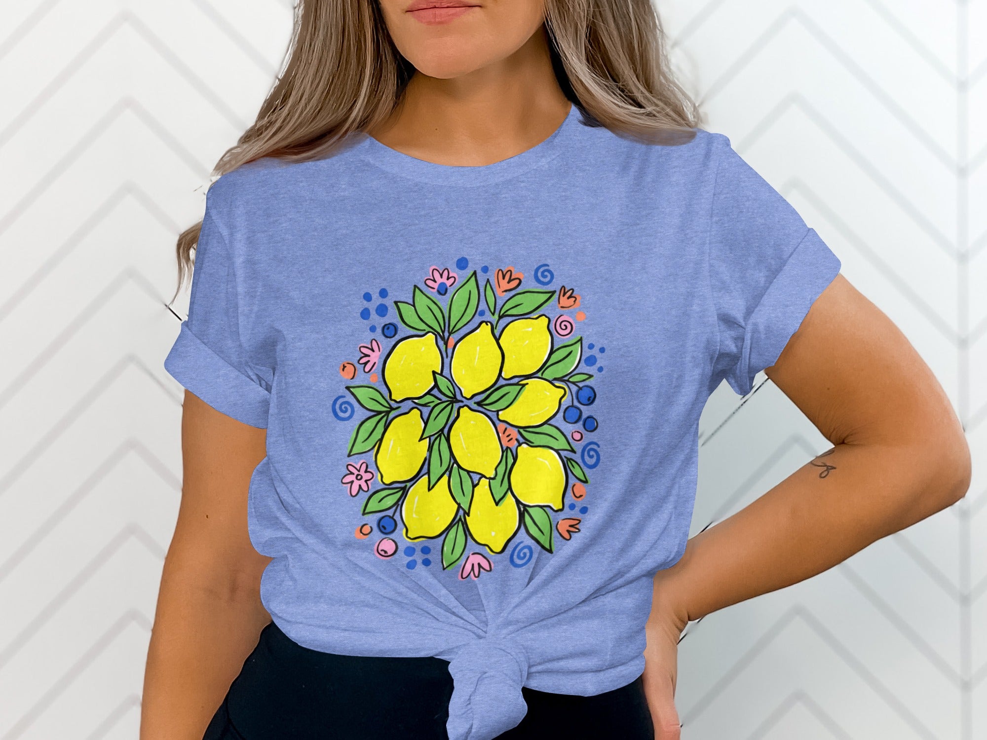 Blue t-shirt with a central illustration of lemons, leaves, and colorful dots and flowers.