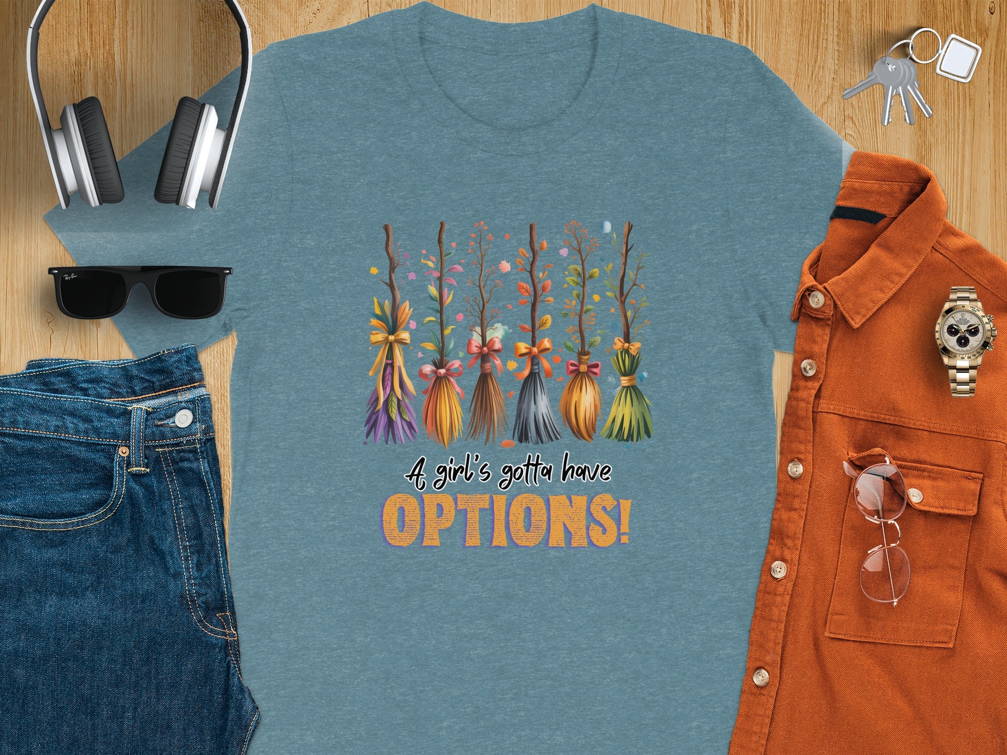 Teal t-shirt with watercolor brooms and text "A girl's gotta have OPTIONS!".