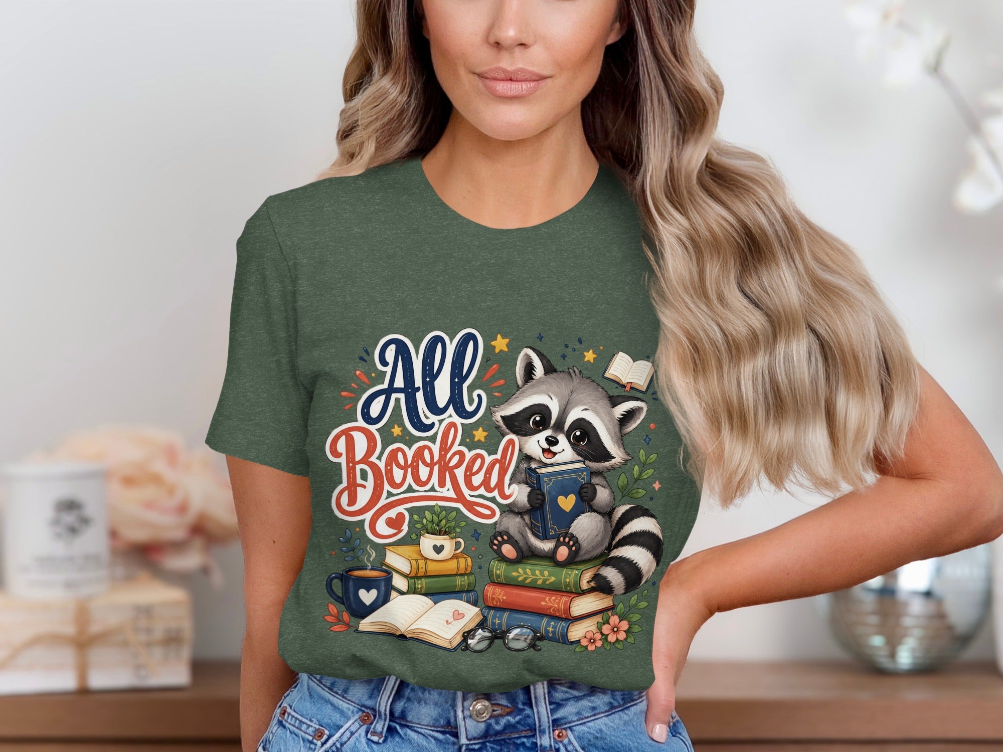 Cute raccoon reading books with "All Booked" text on a green shirt.