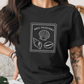 Black t-shirt with white stamp design featuring seashells and text "SHELL COLLECTOR'S".