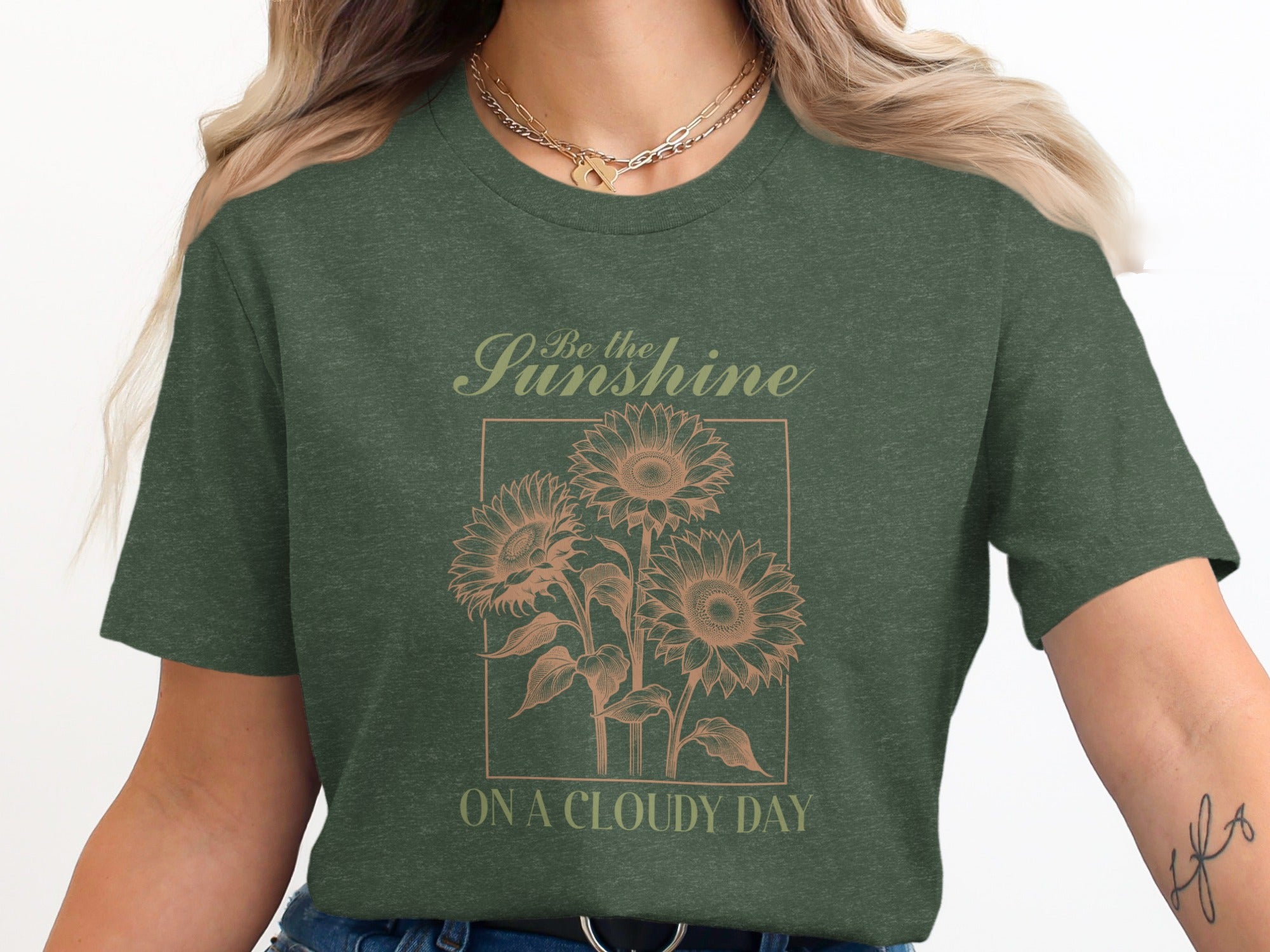 Green t-shirt with "Be the Sunshine On A Cloudy Day" and sunflower graphic.