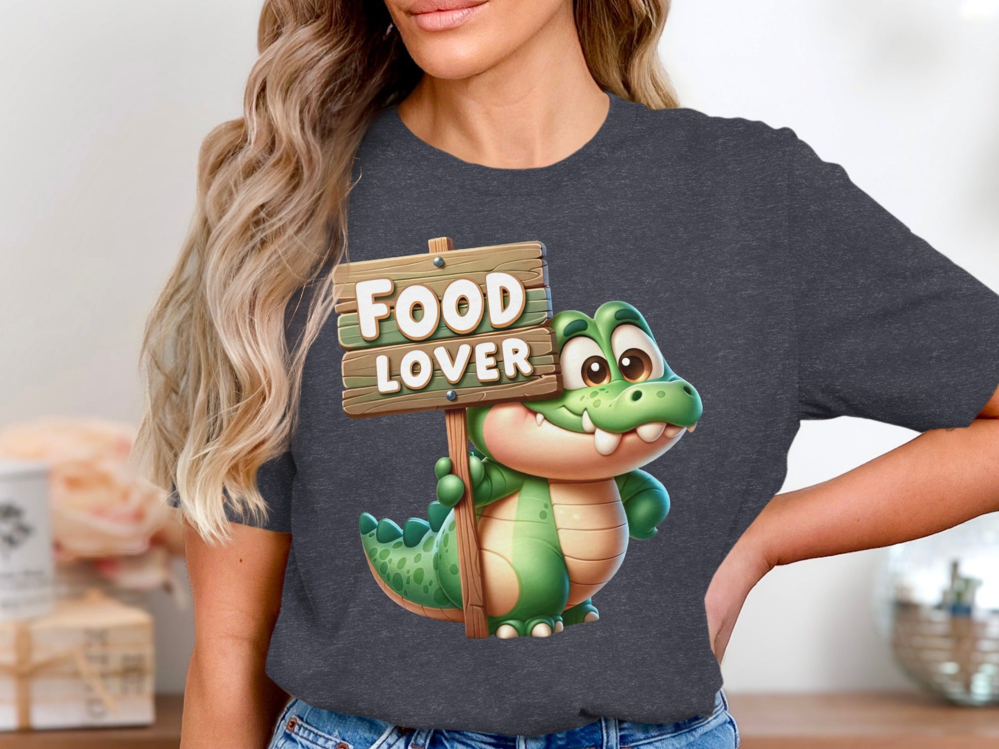 Cartoon alligator holds a wooden sign reading "FOOD LOVER" on a dark gray t-shirt.
