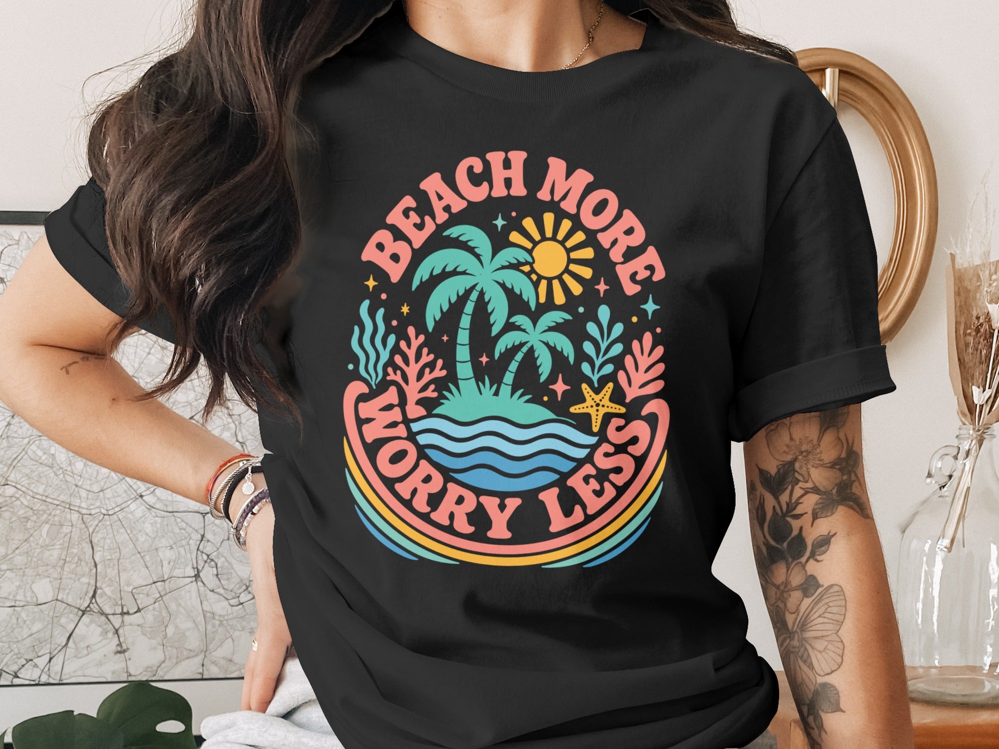 Black t-shirt with "Beach More Worry Less" text and island graphic.