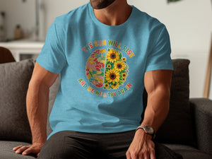 Blue t-shirt with a brain graphic split into patchwork fabric and sunflowers, text says "The sun will rise and we will try again".