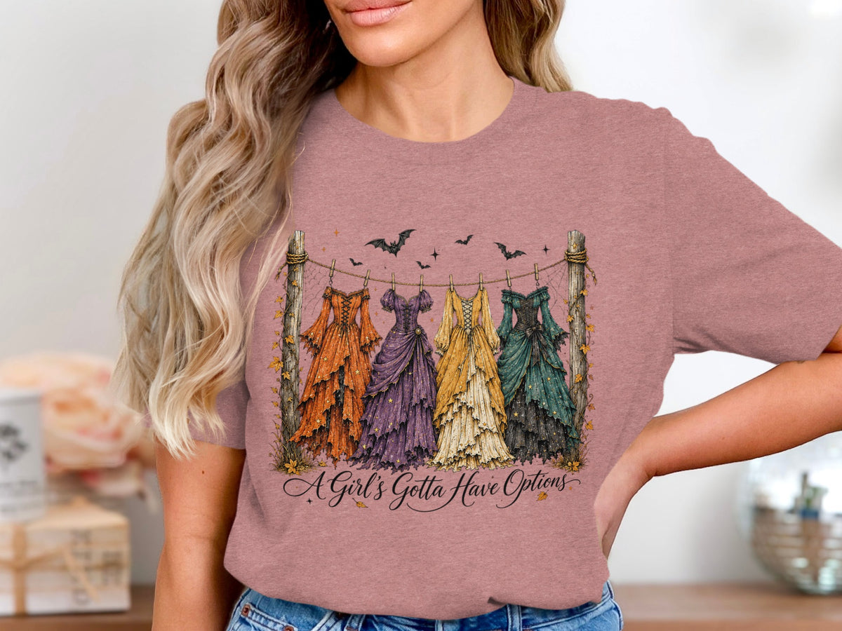 Five dresses hang on a line with bats and leaves, text reads "A Girl's Gotta Have Options."