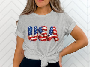 Grey t-shirt with bold "USA" text in American flag colors and patterns.