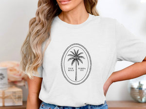 White t-shirt with oval logo featuring a palm tree and text "Palm Beach Florida 1974".