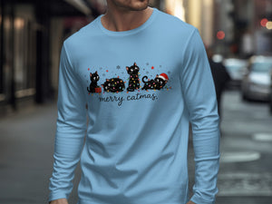 Light blue long-sleeved shirt with a graphic of four black cats tangled in Christmas lights and the text merry catmas.