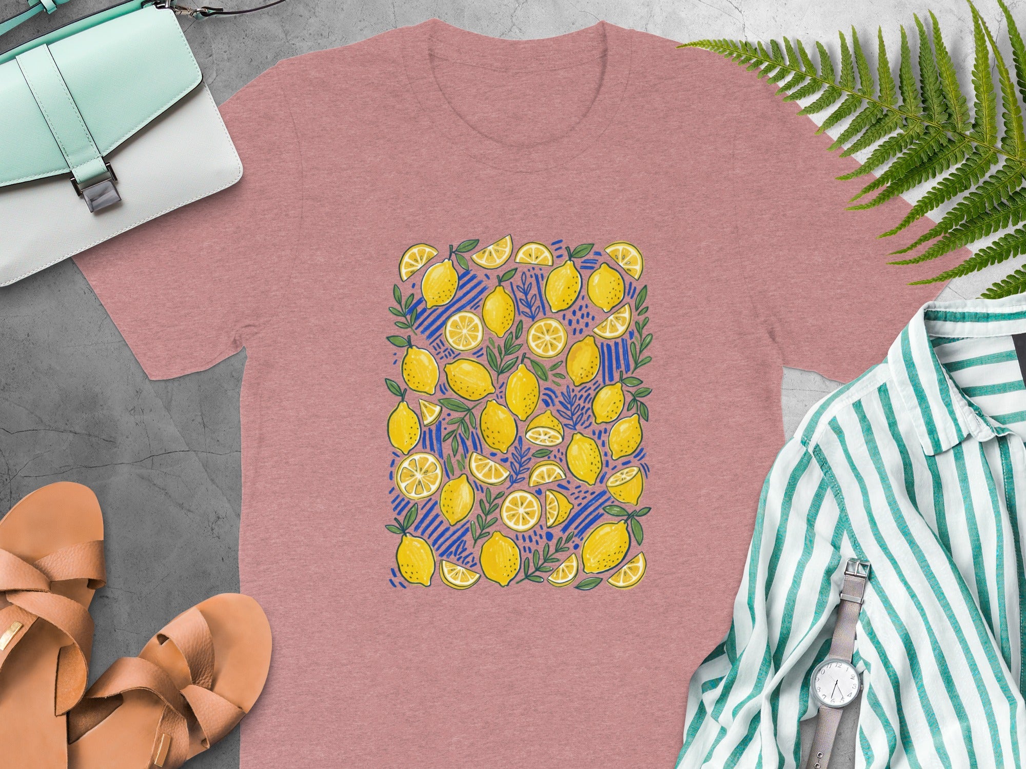 Pink t-shirt with an all-over pattern of yellow lemons, leaves, and blue stripes.