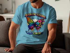 Light blue t-shirt with a graphic of a colorful butterfly and the text "BROKEN CRAYONS STILL COLOR".