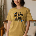 Gold t-shirt with "EAT SLEEP GAME REPEAT" text and gaming graphics.