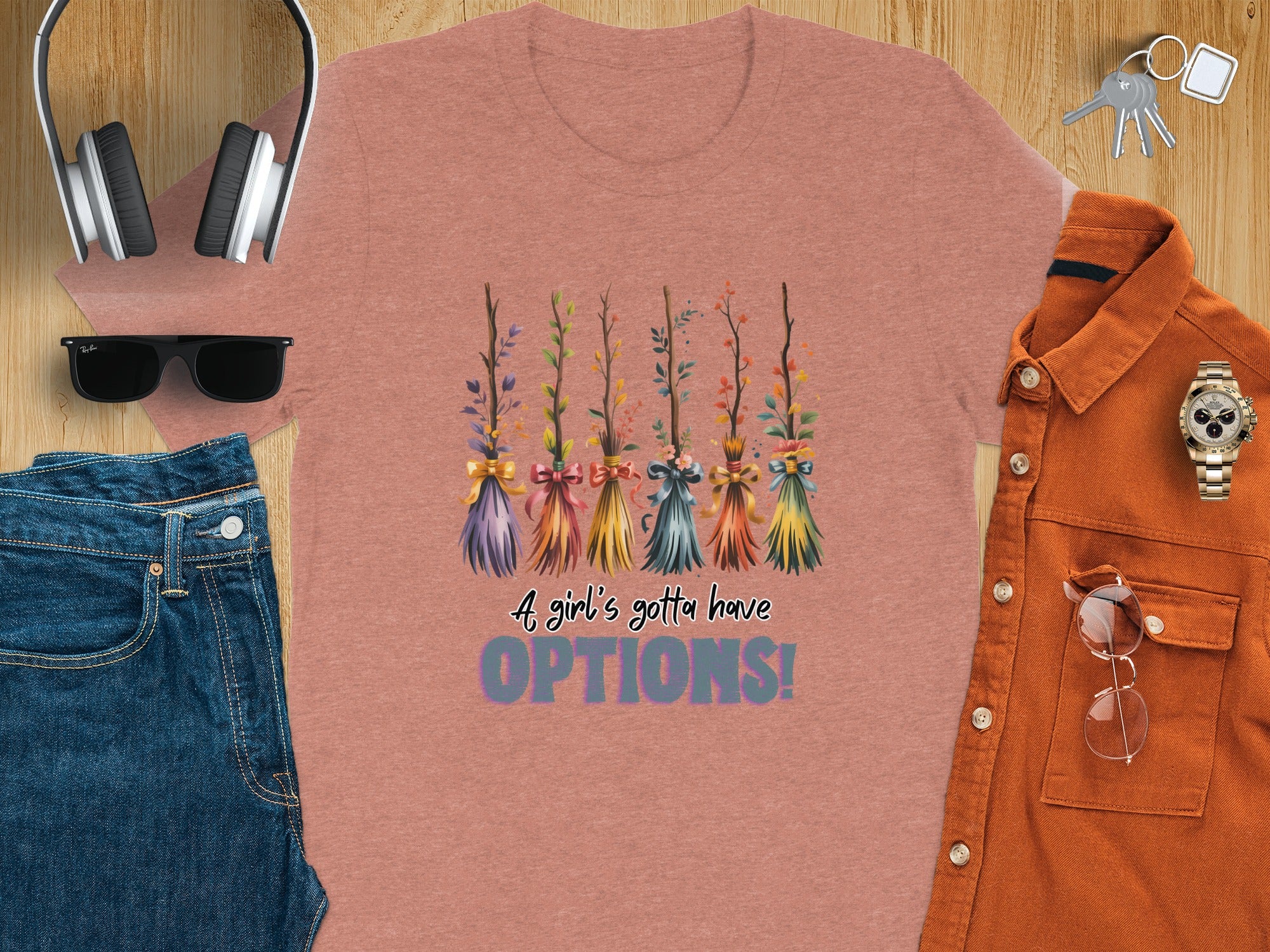 T-shirt with five colorful whimsical brooms and text "A girl's gotta have OPTIONS!"