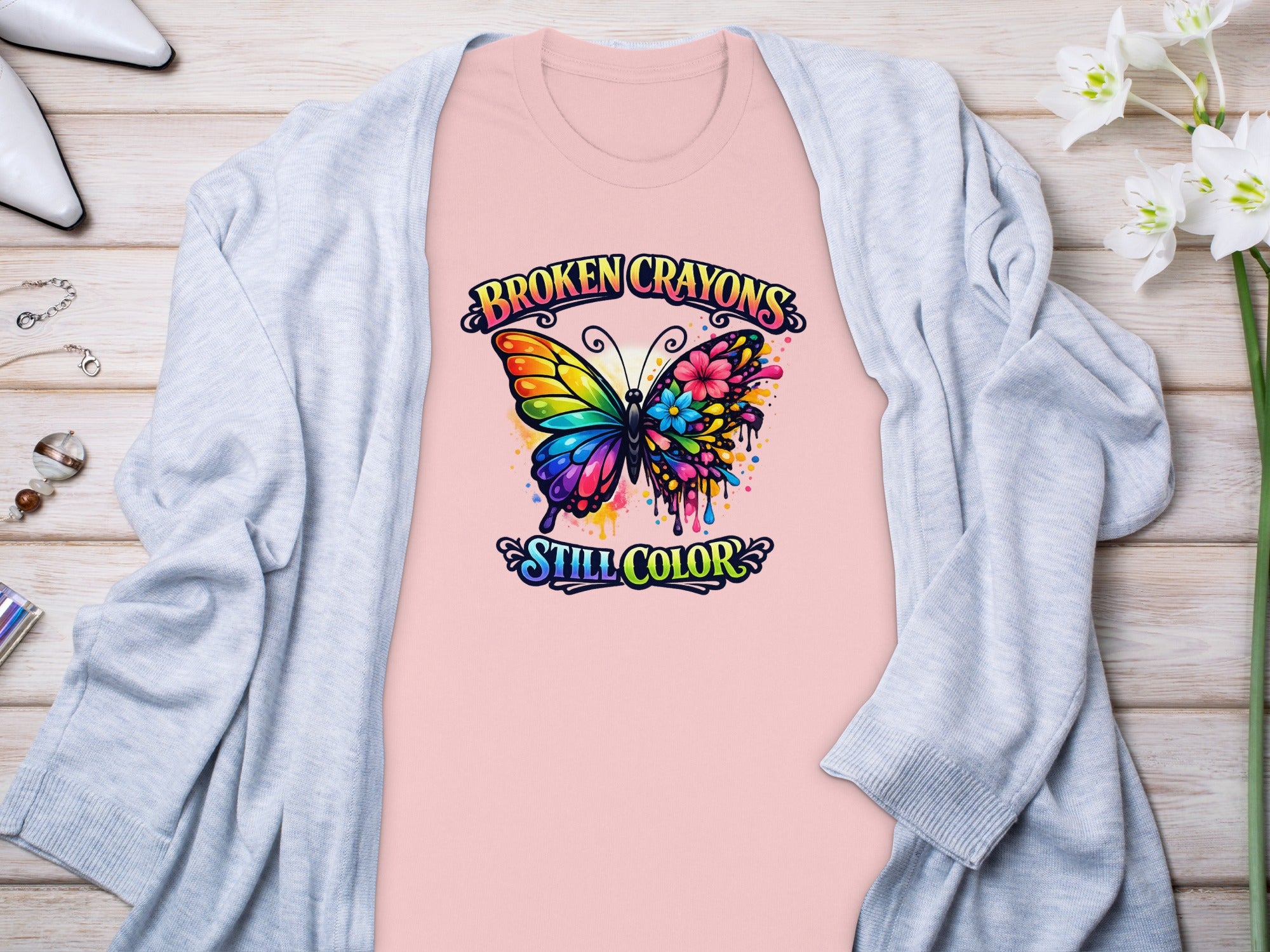 Pink t-shirt with a colorful butterfly graphic and text "BROKEN CRAYONS STILL COLOR".