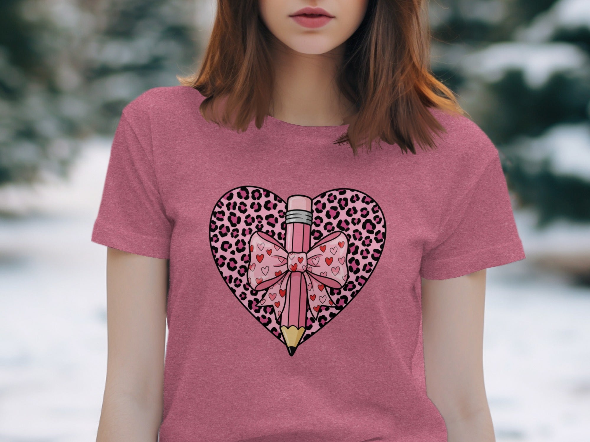 Pink t-shirt with a pink pencil and bow inside a leopard print heart graphic.