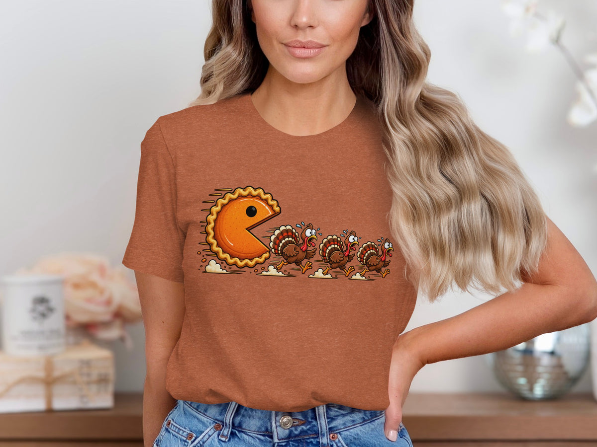 Pie-shaped Pac-Man character chases three cartoon turkeys across t-shirt.